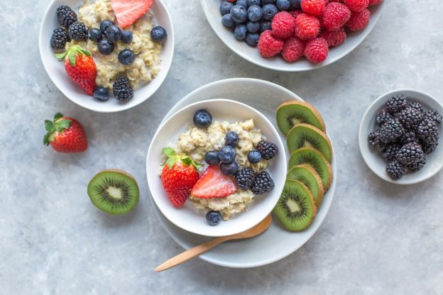 Bowls of oats topped with strawberries, kiwi and blueberries