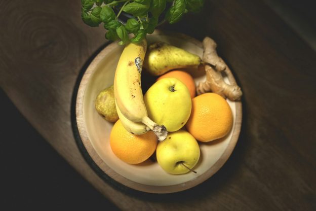 A wooden bowl of bananas, apples and oranges
