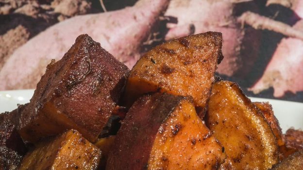 Roasted sweet potato chunks with caramelised, spiced edges piled on a white plate.