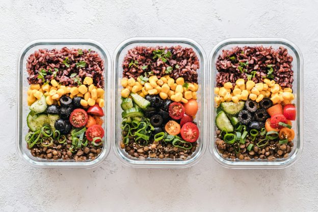 Three lunch containers filled with grains, vegetables and beans